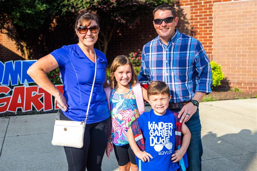 Three people wearing blue smile on the first full day of kindergarten